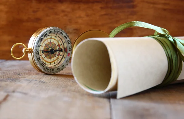 Starý pergamen a starožitný kompas na dřevěný stůl — Stock fotografie