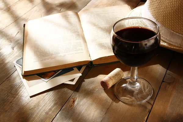 Copa de vino tinto y viejo libro abierto sobre mesa de madera al atardecer estalló. vintage imagen filtrada —  Fotos de Stock