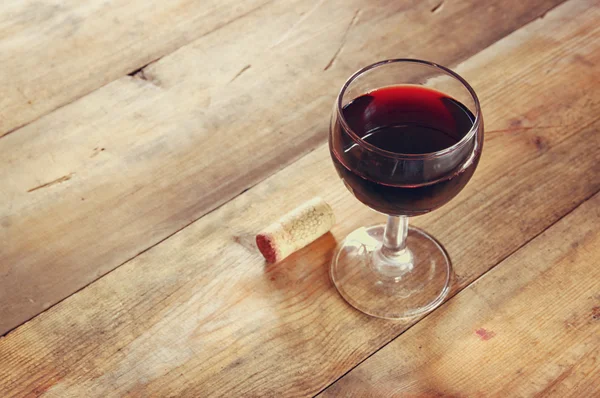 Copa de vino tinto y viejo libro sobre mesa de madera al atardecer estalló. vintage imagen filtrada — Foto de Stock