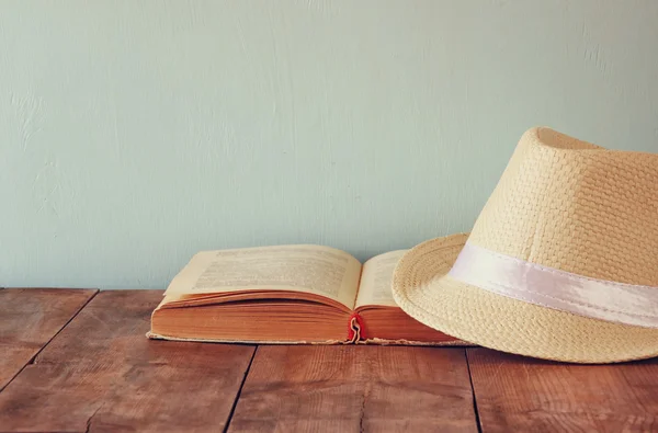 Fedora καπέλο και ανοιχτό βιβλίο πέρα από το ξύλινο τραπέζι — Φωτογραφία Αρχείου