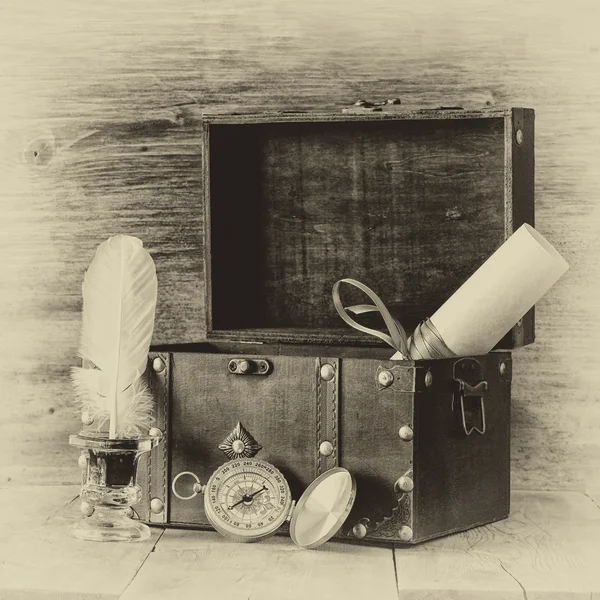 Antique compass, inkwell and old wooden chest on wooden table.  black and white style old photo