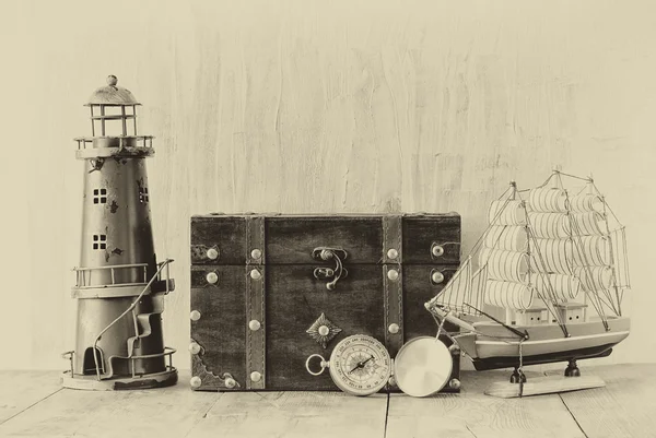 Bussola antica, faro d'epoca, barca in legno e vecchio scrigno su tavolo in legno. in bianco e nero vecchio stile foto — Foto Stock