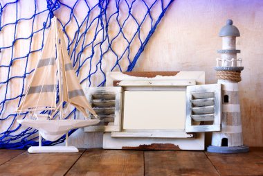 Eski vintage ahşap beyaz çerçeve, deniz feneri ve yelkenli tekne ahşap masa üzerinde. Vintage filtre uygulanan görüntü. Deniz yaşam tarzı kavramı