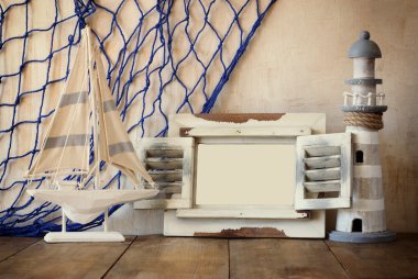 Eski vintage ahşap beyaz çerçeve, deniz feneri ve yelkenli tekne ahşap masa üzerinde. Vintage filtre uygulanan görüntü. Deniz yaşam tarzı kavramı