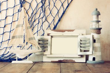 Eski vintage ahşap beyaz çerçeve, deniz feneri ve yelkenli tekne ahşap masa üzerinde. Vintage filtre uygulanan görüntü. Deniz yaşam tarzı kavramı