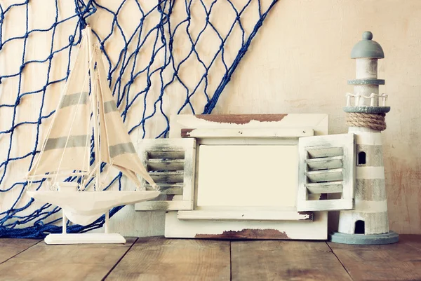 Eski vintage ahşap beyaz çerçeve, deniz feneri ve yelkenli tekne ahşap masa üzerinde. Vintage filtre uygulanan görüntü. Deniz yaşam tarzı kavramı