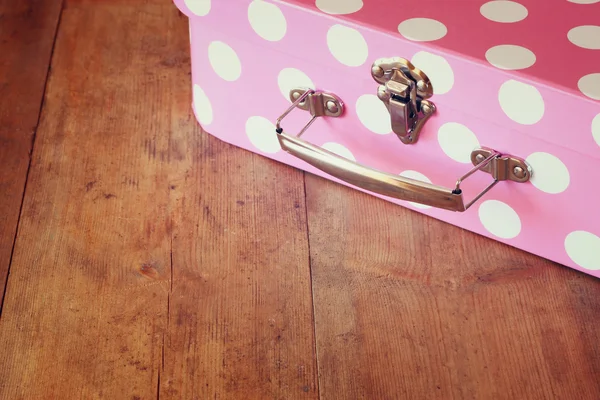 Imagen de cerca de la maleta rosa con lunares sobre una mesa de madera — Foto de Stock