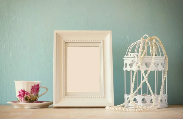 Vintage classica cornice bianca su tavolo in legno con tazza di porcellana e lanterna — Foto Stock