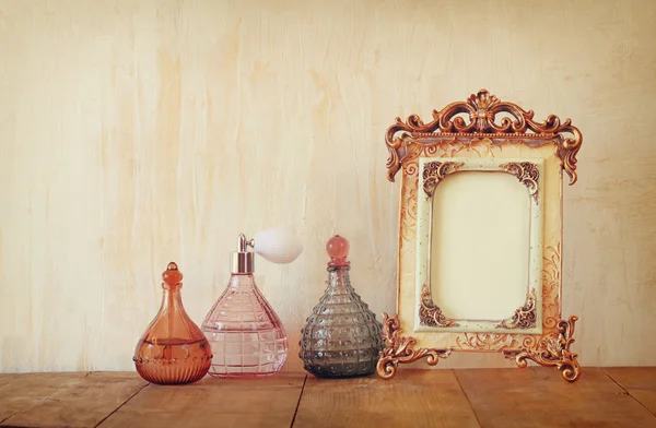 Image of victorian vintage antique classical frame and perfume bottle on wooden table. filtered image — Stock Photo, Image