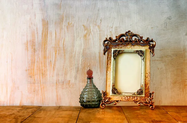 Image of victorian vintage antique classical frame and perfume bottle on wooden table. filtered image — Stock Photo, Image