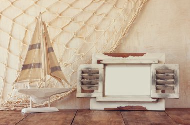 Eski vintage ahşap beyaz çerçeve ve yelkenli tekne ahşap masa üzerinde. Vintage filtre uygulanan görüntü. Deniz yaşam tarzı kavramı