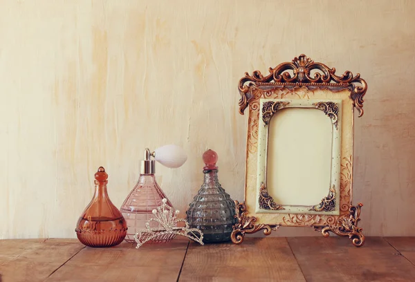Imagem de vitoriano vintage antigo quadro clássico, coroa de diamantes e frascos de perfume na mesa de madeira. imagem filtrada — Fotografia de Stock