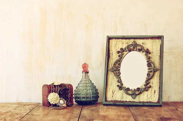 Image of victorian vintage antique classical frame, jewelry and perfume bottles on wooden table. filtered image — Stock Photo, Image