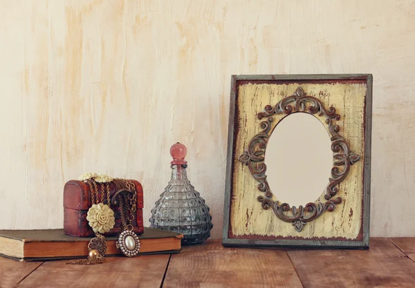 Image of victorian vintage antique classical frame, jewelry and perfume bottles on wooden table. filtered image — Stock Photo, Image