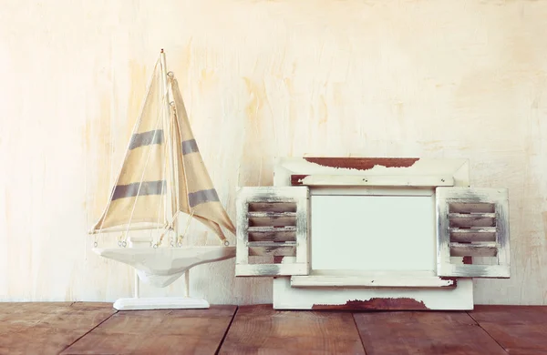 Antiguo marco blanco de madera vintage y velero sobre mesa de madera. vintage imagen filtrada. concepto de estilo de vida náutico —  Fotos de Stock