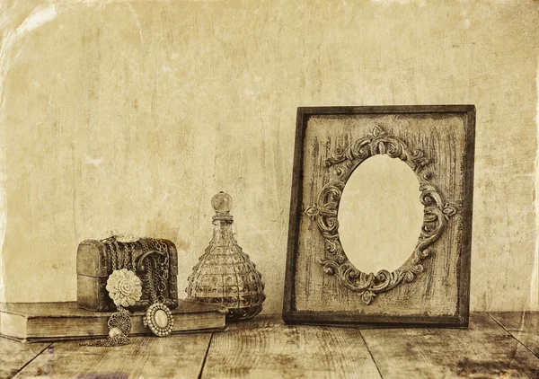 Image of victorian vintage antique classical frame, jewelry and perfume bottles on wooden table. old style photo — Stock Photo, Image