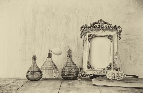 Image of victorian vintage antique classical frame and perfume bottles on wooden table. filtered image — Stock Photo, Image