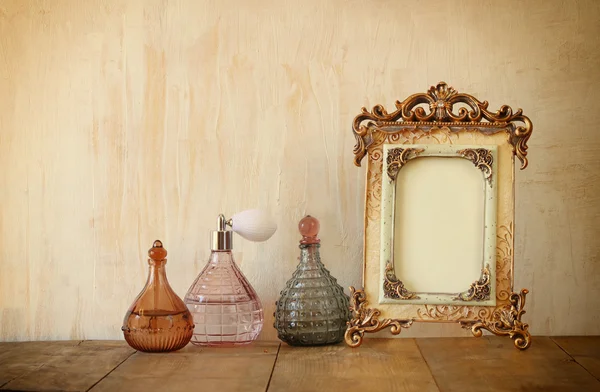 Image of victorian vintage antique classical frame and perfume bottles on wooden table. filtered image — Stock Photo, Image