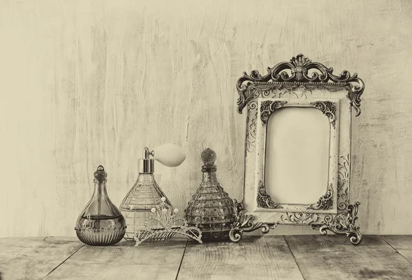 Image of victorian vintage antique classical frame, jewelry and perfume bottles on wooden table. old style photo — Stock Photo, Image