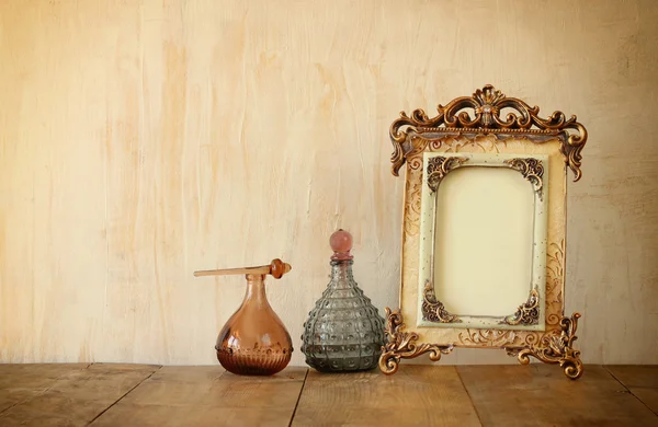 Obrázek viktoriánské vintage starožitný klasický rám a parfém lahví na dřevěný stůl. filtrovaný obraz — Stock fotografie