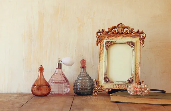 Immagine della cornice classica d'epoca vittoriana, gioielli e bottiglie di profumo sul tavolo di legno. immagine filtrata — Foto Stock