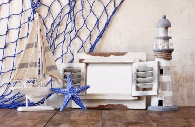 Eski vintage ahşap beyaz çerçeve, deniz feneri ve yelkenli tekne ahşap masa üzerinde. Vintage filtre uygulanan görüntü. Deniz yaşam tarzı kavramı