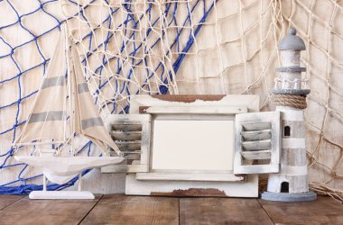 Eski vintage ahşap beyaz çerçeve, deniz feneri ve yelkenli tekne ahşap masa üzerinde. Vintage filtre uygulanan görüntü. Deniz yaşam tarzı kavramı