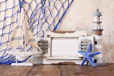 Eski vintage ahşap beyaz çerçeve, deniz feneri ve yelkenli tekne ahşap masa üzerinde. Vintage filtre uygulanan görüntü. Deniz yaşam tarzı kavramı