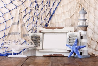 Eski vintage ahşap beyaz çerçeve, deniz feneri ve yelkenli tekne ahşap masa üzerinde. Vintage filtre uygulanan görüntü. Deniz yaşam tarzı kavramı