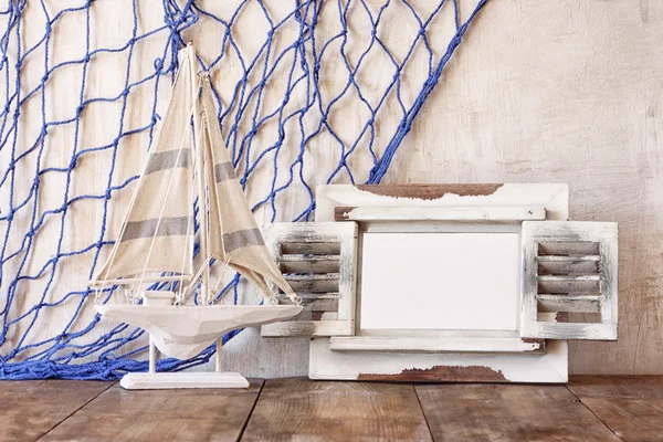 Eski vintage ahşap beyaz çerçeve ve yelkenli tekne ahşap masa üzerinde. Vintage filtre uygulanan görüntü. Deniz yaşam tarzı kavramı