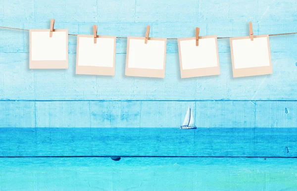 Old polaroid photo frames hnaging on a rope with double exposure image of sailboat at horizon on the sea and wooden planks background — Stock Photo, Image