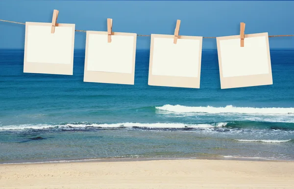 Gamla polaroid foto ramar hnaging på ett rep med beach bakgrund — Stockfoto