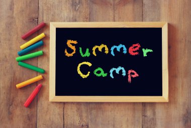 Blackboard bu ve renkli boya kalemi ahşap arka plan üzerinde yazılı ifade yaz kampı ile Üstten Görünüm