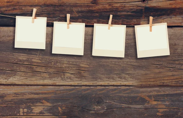 Old polaroid photo frames hanging on a rope with wooden background