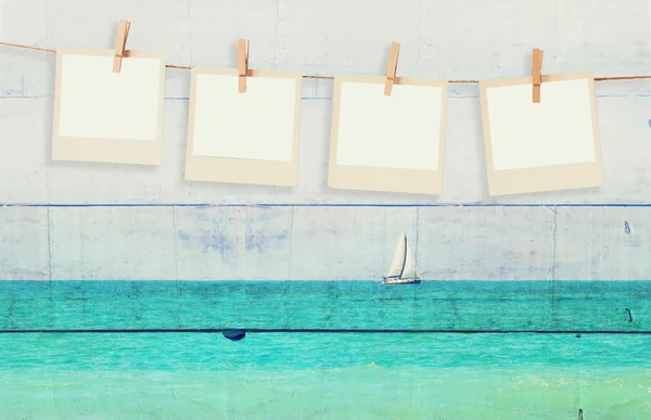 Antiguos marcos de fotos polaroid colgando en una cuerda con doble exposición imagen de velero en el horizonte en el mar y tablones de madera de fondo — Foto de Stock