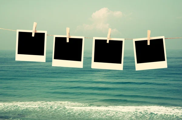 old polaroid photo frames hanging on a rope with beach background