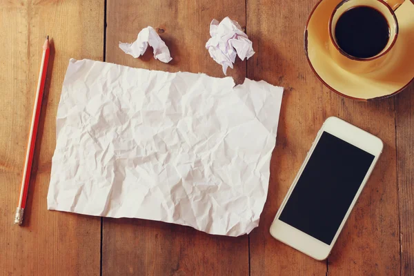 Top view image of crumpled blank paper, cup of coffee and smartphone over wooden table — Stock Photo, Image