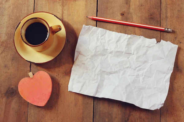 Top view image of empty crumpled paper, coffee cup and heart shape over wooden table — Stock Photo, Image