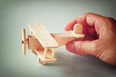ahşap oyuncak uçak ahşap arka plan üzerinde tutan adamın el fotoğrafı kapatın. Filtre uygulanan görüntü. aspirasyon ve sadelik kavramı