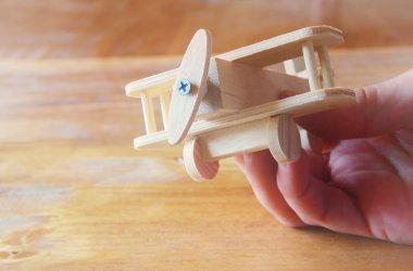 ahşap oyuncak uçak ahşap arka plan üzerinde tutan adamın el fotoğrafı kapatın. Filtre uygulanan görüntü. aspirasyon ve sadelik kavramı