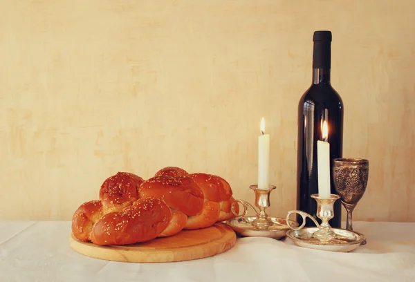 Shabbat-Image. Challah-Brot, Shabbat-Wein und Kerzenleuchter auf einem Holztisch. Vintage gefiltertes Bild — Stockfoto