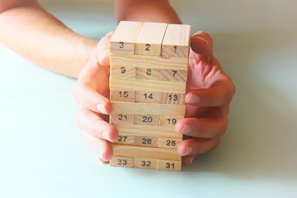 Manlig hand utsläppande av trä block på ett torn. hyvling och strategi koncept — Stockfoto