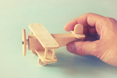 ahşap oyuncak uçak ahşap arka plan üzerinde tutan adamın el fotoğrafı kapatın. Filtre uygulanan görüntü. aspirasyon ve sadelik kavramı