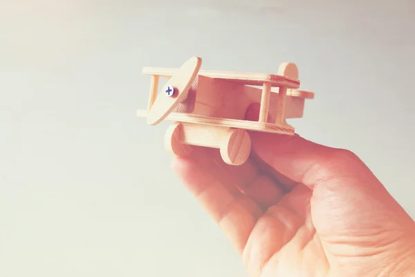 Cerrar la foto de la mano del hombre sosteniendo el avión de juguete de madera sobre el fondo de madera. imagen filtrada. concepto de aspiración y simplicidad —  Fotos de Stock