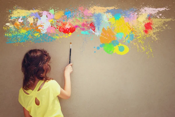 Arkadan görünüş şirin çocuk fırça tutarak dokulu duvar ve su sıçramalarına boya — Stok fotoğraf