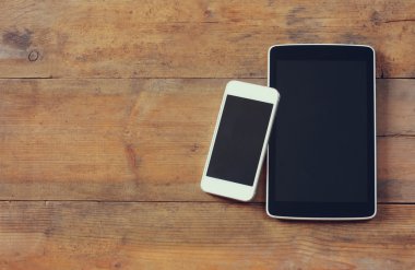 top view image of smartphone and tablet device over wooden table room for text, ready for mockup.