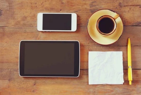 Top view image of tablet device, coffee and paper note over wooden background — Stockfoto