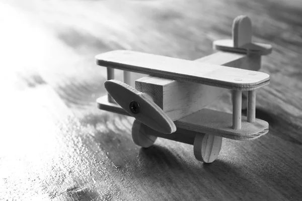 Houten vliegtuig speelgoed over gestructureerde houten achtergrond. retro stijl beeld. zwart / wit oude stijl foto — Stockfoto