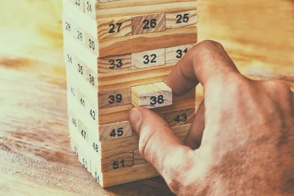 Manlig hand utsläppande av trä block på ett torn. hyvling och strategi koncept — Stockfoto