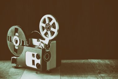 old 8mm Film Projector over wooden table and textured background clipart